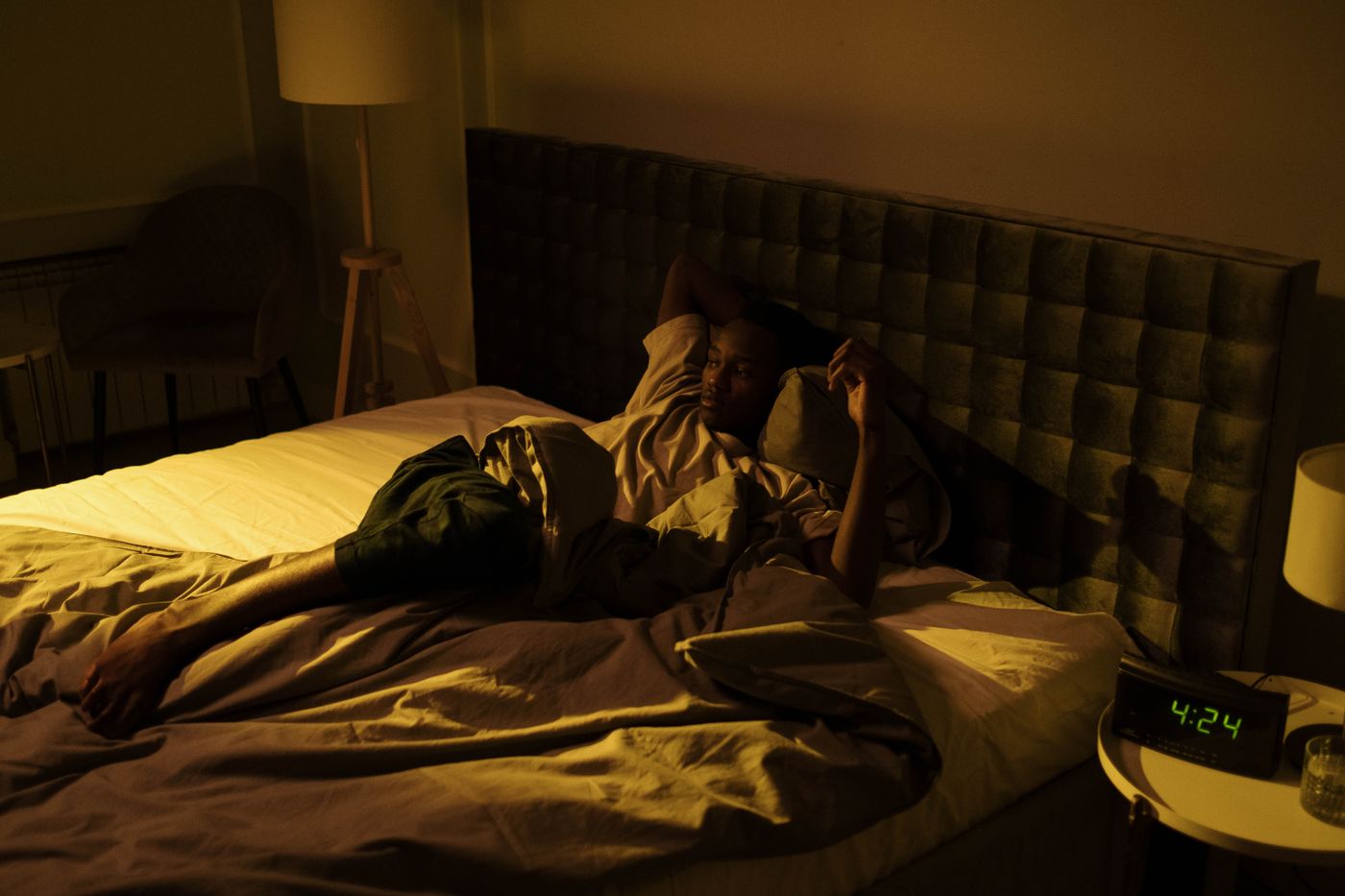 He is awake, lying on his back in the lamplight