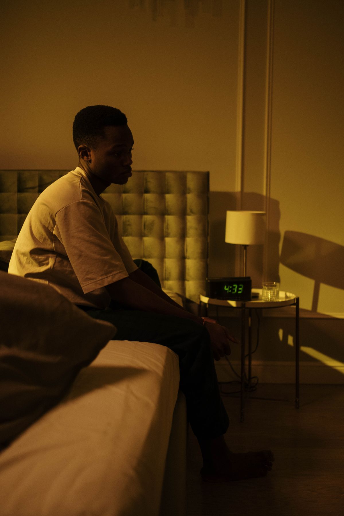 A man sitting on the edge of the bed in the middle of the night